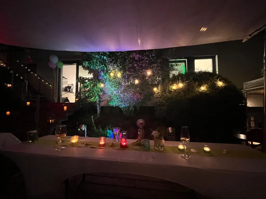 Abendlich beleuchtete Tafel mit Kerzen, Gläsern und Lichterketten im Garten beim Sommerfest 2025