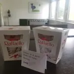 Zwei Packungen Pralinen mit handgeschriebenem Zettel auf einem Tisch im Büro, Dank an Praktikant:innen