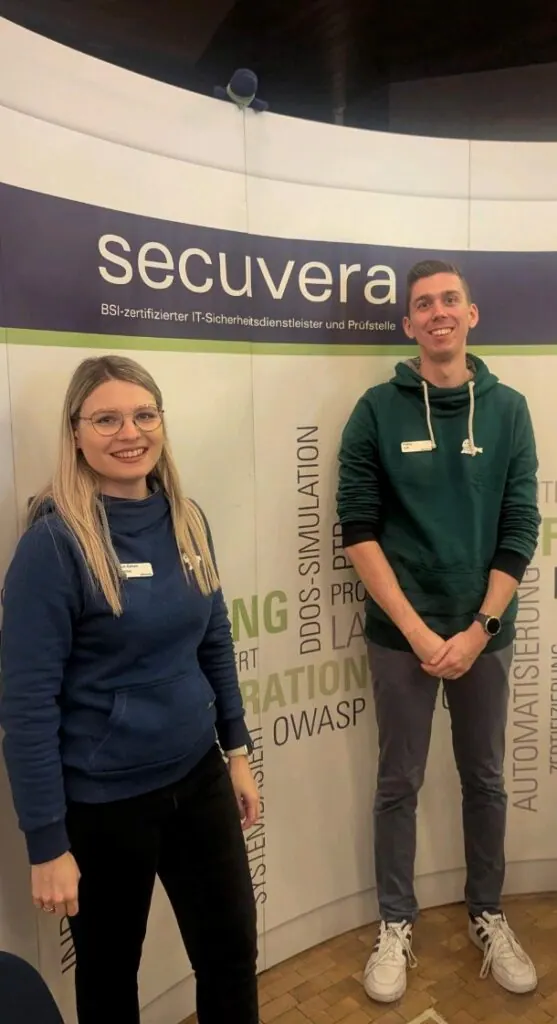 Zwei Mitarbeitende von secuvera vor der Messewand beim IT-Mittelstandstag der Hochschule Esslingen
