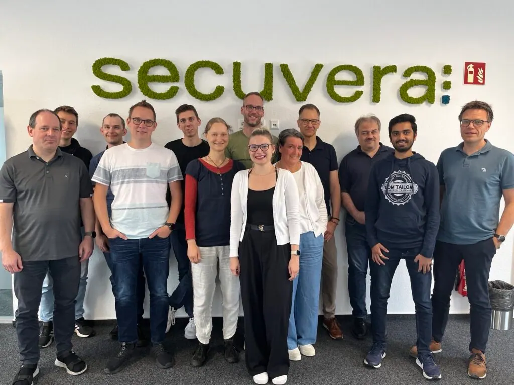 Gruppenbild von Teilnehmenden des Kommunikationstrainings 2024 vor dem secuvera-Schriftzug im Büro