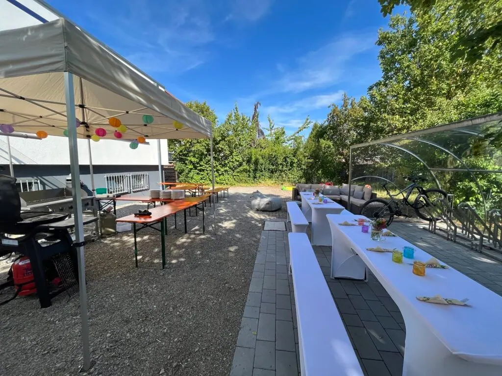 Außengelände bei secuvera mit Pavillon, Bierbänken, Grill und Lampions, vorbereitet für das Sommerfest 2023