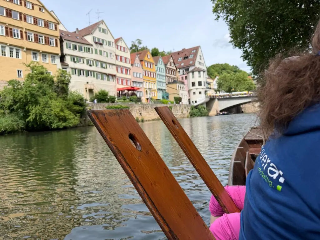 Stocherkahnfahrt in Tübingen mit Blick auf bunte Altstadthäuser, vorn eine Person im secuvera-Hoodie