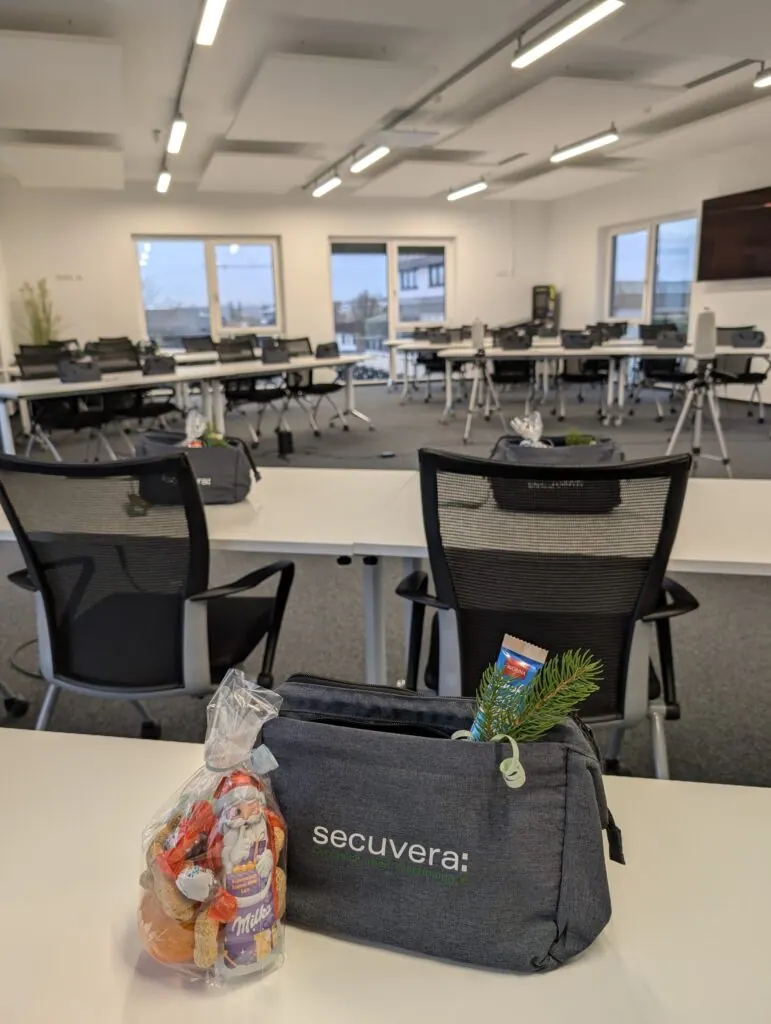 Weihnachtsgeschenk mit Schokoweihnachtsmann, Plätzchen und Tannenzweig auf einer secuvera-Tasche im Meetingraum