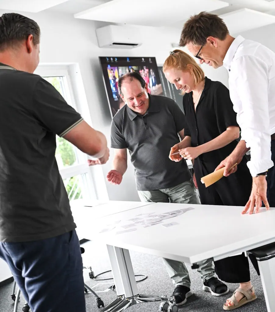 Vier Teilnehmende des Werte-Workshops von secuvera legen Karten auf einem Tisch aus und besprechen sie