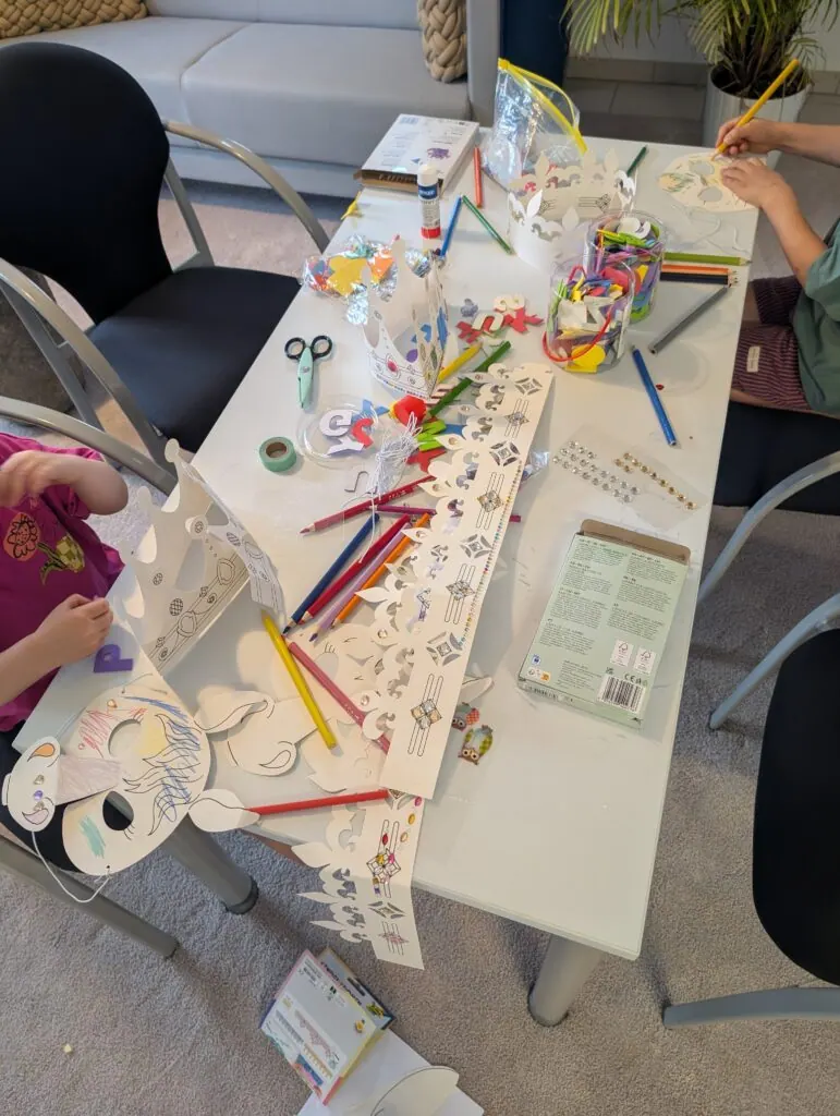 Kinderbasteltisch mit Buntstiften, Papierkronen und Masken beim Sommerfest 2026