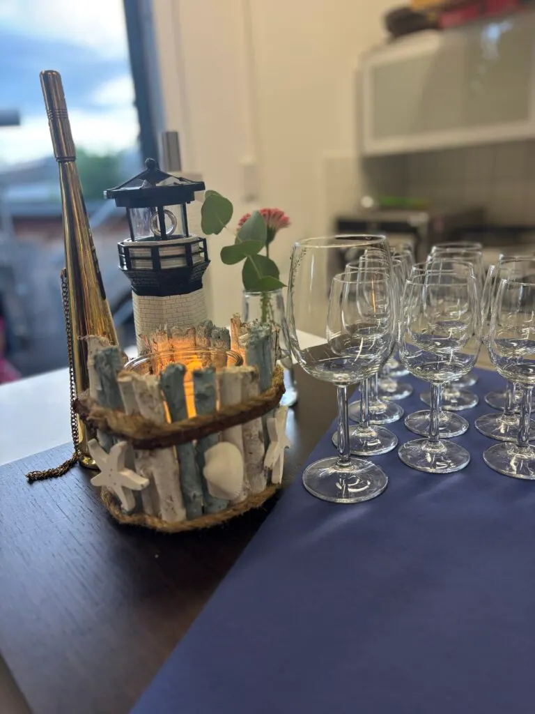 Maritime Dekoration mit Leuchtturm und Muschelwindlicht neben Weingläsern in der Büroküche