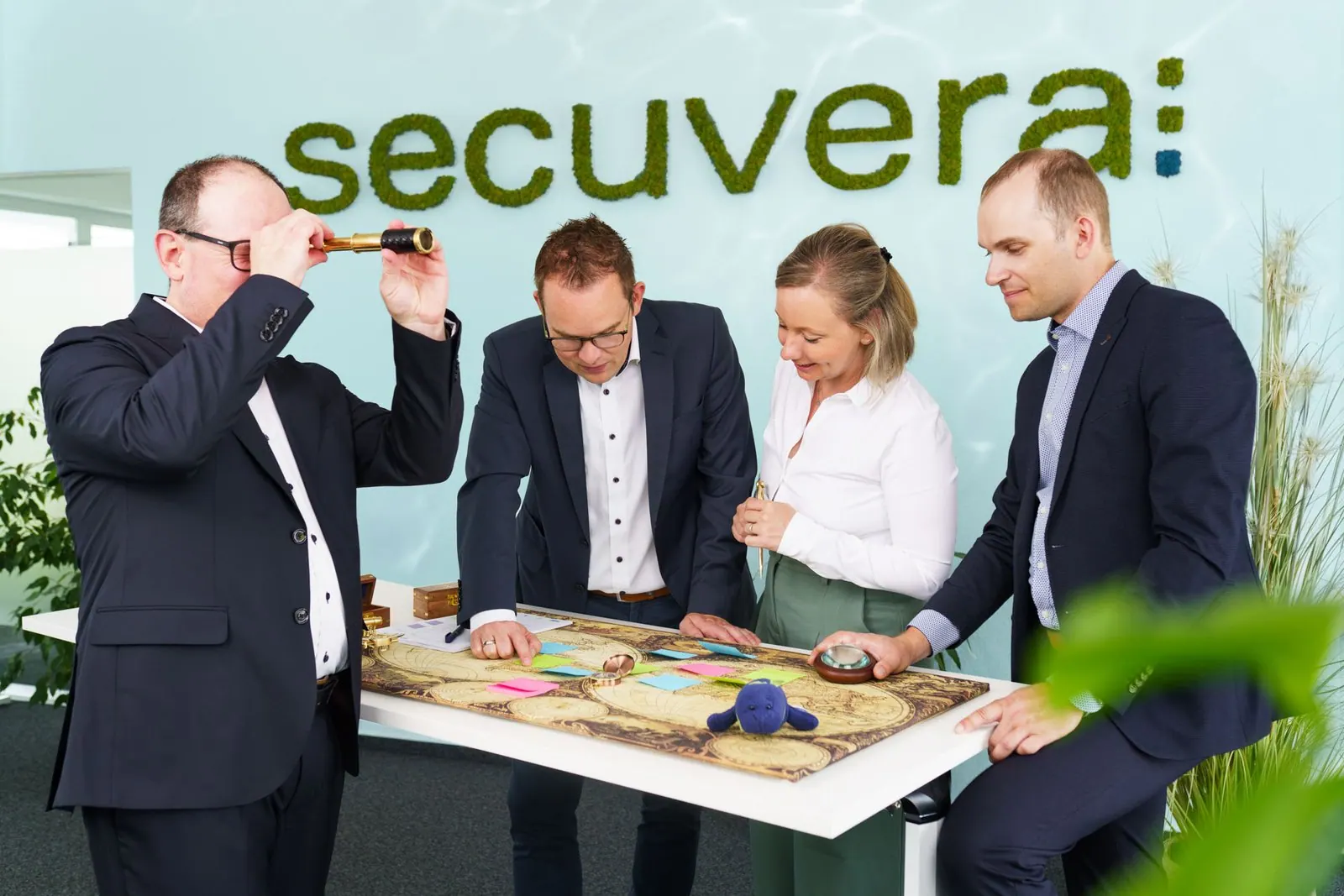 The secuvera team planning at a map beneath the green secuvera lettering